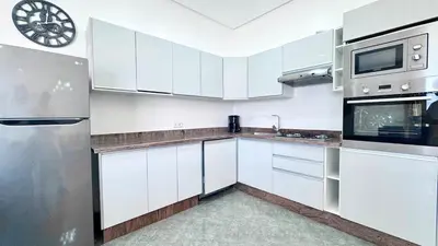 a kitchen with white cabinets and a clock on the wall at New Villa Dali & Spa Paddel Marrakech in Marrakech