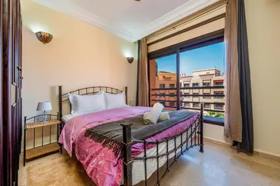 a bedroom with a bed and a large window at Cocon Ocre Pool and Balcony in Marrakech