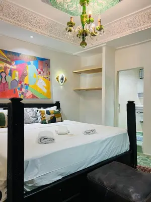 a bedroom with a bed with a painting on the wall at Riad Dar L artiste in Marrakech