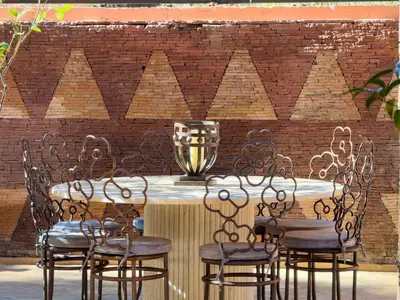 a table with chairs and a trophy on a brick wall at JARDIN VITTORIO - Marrakech - Hivernage - Heated & Luxury Pool in Marrakech