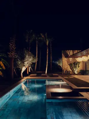 a swimming pool at night with palm trees at LA VILLA 58 - Ecolodge - Marrakech in Marrakech