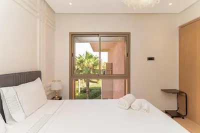 a bedroom with a large white bed and a window at Luxury 3BD Golf View Pool Fast Fiber WiFi in Marrakech