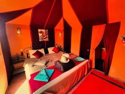 a bedroom with a large bed with orange walls at Yassen luxury camp in Marrakech
