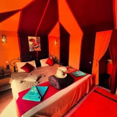 a bedroom with a large bed with red and orange walls at Yassen luxury camp in Marrakech