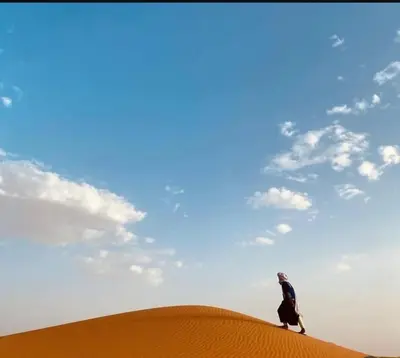 a man walking on top of a sand dune at Yassen luxury camp in Marrakech