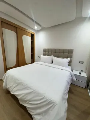 a bedroom with a large white bed with white sheets at Appartement moderne avec terrasse vue piscine in Marrakech