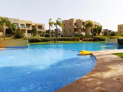 a large swimming pool with a yellow boat in it at Jubaea Prestigia Cosy appartement avec vue sur Atlas à Marrakech in Marrakech