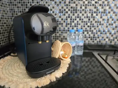 a coffee maker on a table with two bottles of water at Jubaea Prestigia Cosy appartement avec vue sur Atlas à Marrakech in Marrakech