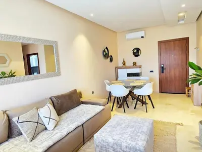 a living room with a couch and a table at Jubaea Prestigia Cosy appartement avec vue sur Atlas à Marrakech in Marrakech