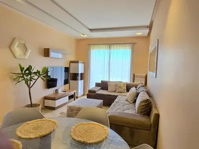 a living room with a couch and a table at Jubaea Prestigia Cosy appartement avec vue sur Atlas à Marrakech in Marrakech