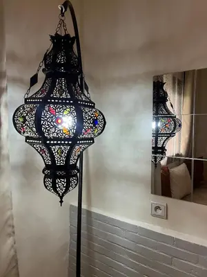 a black chandelier hanging from a wall next to a mirror at Appartement spacieux 1min Menara Mall 5mins de gare ferroviaire in Marrakech