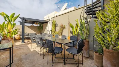 a table and chairs on a patio with plants at Riad Awajana Marrakech - Piscine - Jacuzzi in Marrakech