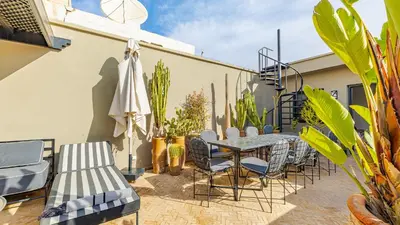 a patio with a table and chairs and plants at Riad Awajana Marrakech - Piscine - Jacuzzi in Marrakech