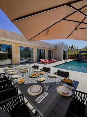 a dining table with plates of food on it next to a pool at MIKESTAY - Villa Sherazade in Marrakech