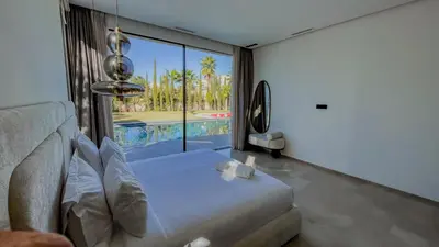 a bedroom with a bed and a large window with a pool at MIKESTAY - Villa Sherazade in Marrakech