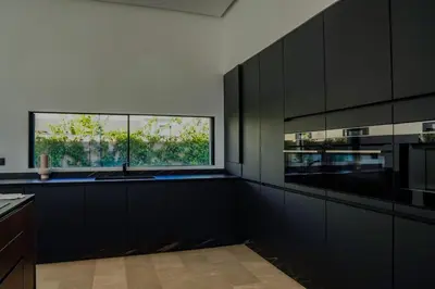 a kitchen with black cabinets and a large window at MIKESTAY - Villa Sherazade in Marrakech