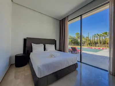 a bedroom with a bed and a view of a pool at MIKESTAY - Villa Sherazade in Marrakech