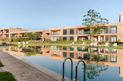 an apartment complex with a reflection in a body of water at Marrakesh, Noria Residence, Luxury 1BR, Atlas View in Marrakech