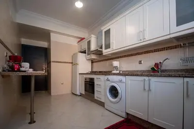 a kitchen with white cabinets and a washing machine at Calm Apartment with Pool in Geuliz marrakech Close to Medina in Marrakech