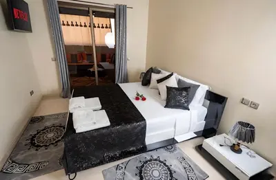 a bedroom with a black and white bed and a mirror at Calm Apartment with Pool in Geuliz marrakech Close to Medina in Marrakech