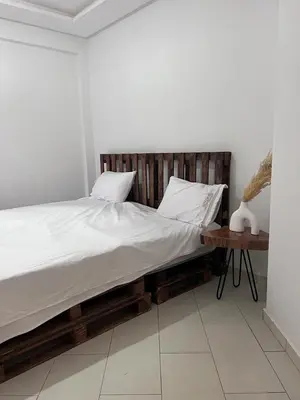 a bed with white sheets and pillows and a table at Modern quiet studio Close to Guéliz in Marrakech