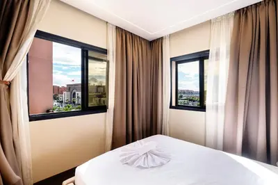 a bedroom with a white bed and two windows at Exceptional Apartment Overlooking Marrakech Train Station in Marrakech