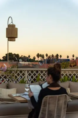 a woman sitting on a couch with a glass of wine at Almaha Marrakech Restaurant & SPA in Marrakech