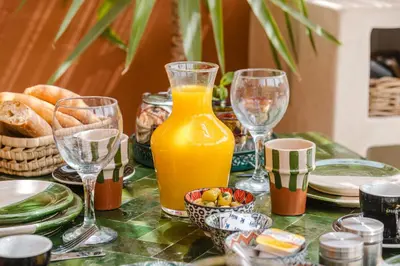 a table with glasses of orange juice and bread at 3BR Gueliz , Rooftop Heated Pool , 10 min Jamaa el Fna, in Marrakech