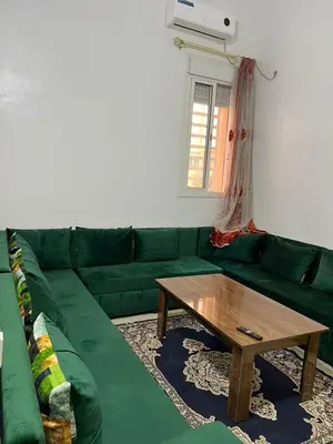 a green couch with a coffee table in a living room at Modern Apartment & 8 min from Marrakech Airport in Marrakech