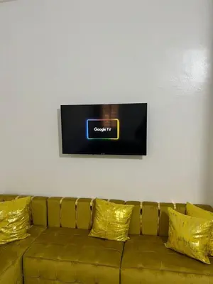 a couch with yellow pillows and a tv on a wall at Modern Apartment & 8 min from Marrakech Airport in Marrakech
