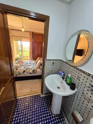 a bathroom with a sink and a bed and a mirror at Appartement centre ville Gueliz in Marrakech