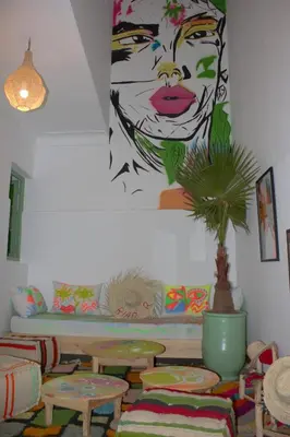 a room with tables and a painting of a woman at Riad R Art in Marrakech