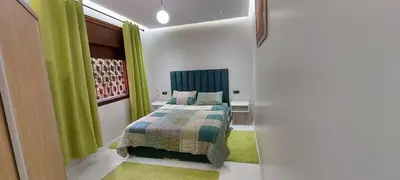 a bedroom with a bed and green curtains at HU Aappartement in Marrakech