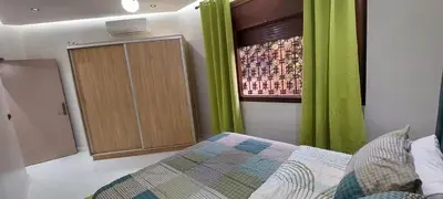 a bedroom with green curtains and a bed and a cabinet at HU Aappartement in Marrakech
