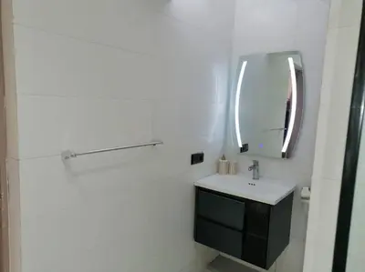 a white bathroom with a sink and a mirror at HU Aappartement in Marrakech