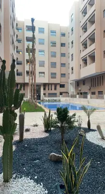 a courtyard with cacti and plants in front of a building at Luxury 2-room apartment - Pool view in Marrakech