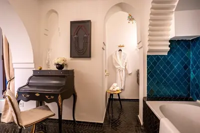 a bathroom with a tub and a piano next to a sink at Riad Anaqa in Marrakech