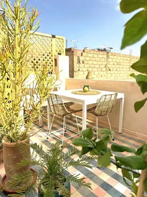 a white table and chairs on a patio with plants at Douiria des Loulous in Marrakech