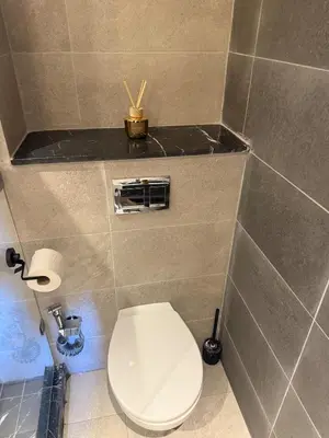 a bathroom with a white toilet in a tiled room at Appartement Haut standing Gueliz, Piscines, jacuzzi chauffé & Fitness in Marrakech
