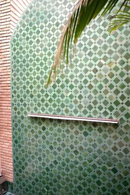 a green tile wall with a metal shelf on it at Riad Garden View in Marrakech