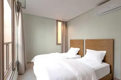 two beds in a bedroom with white sheets at Riad Garden View in Marrakech