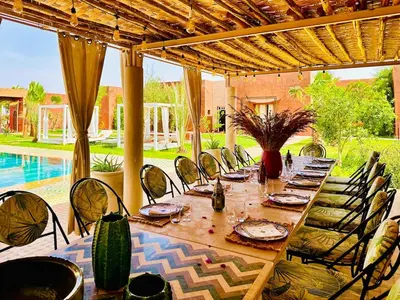 a long wooden table and chairs on a patio at Villa Romana in Marrakech