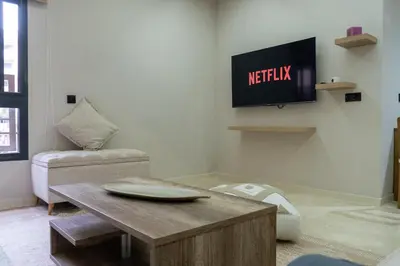 a living room with a tv and a table at luxury white & beige Apartment in Marrakech
