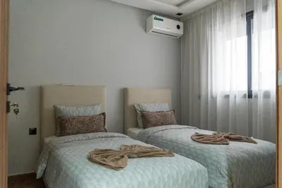 two beds sitting next to each other in a bedroom at luxury white & beige Apartment in Marrakech