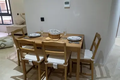 a wooden table with chairs and plates and wine glasses at luxury white & beige Apartment in Marrakech