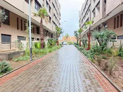 a cobblestone street with palm trees and buildings at luxury white & beige Apartment in Marrakech