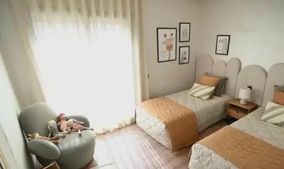 a bedroom with two beds and a woman sitting in a chair at Luxury Apartment in Marrakech