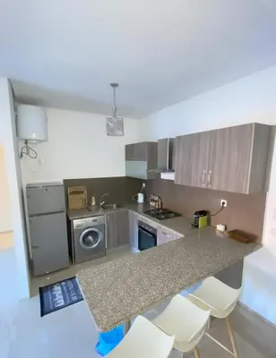 a kitchen with a counter with white chairs in it at Studio Premium au Cœur de Guéliz in Marrakech