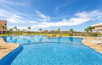a large blue swimming pool with chairs and palm trees at Prestigia Golf Resort Luxury in Marrakech