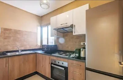 a kitchen with wooden cabinets and a stove top oven at Prestigia Golf Resort Luxury in Marrakech